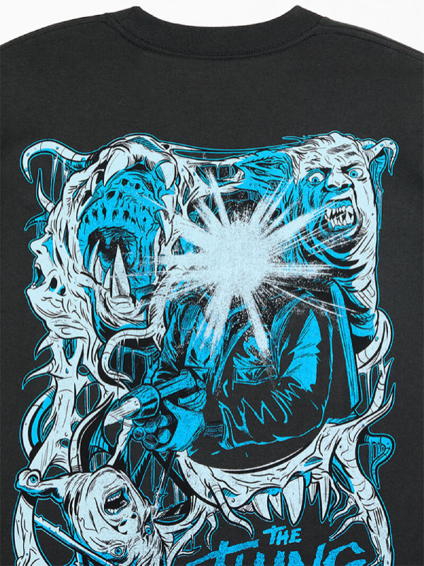 Close-up of black t-shirt front print showing The Thing logo, tagline, and pink melting face graphic